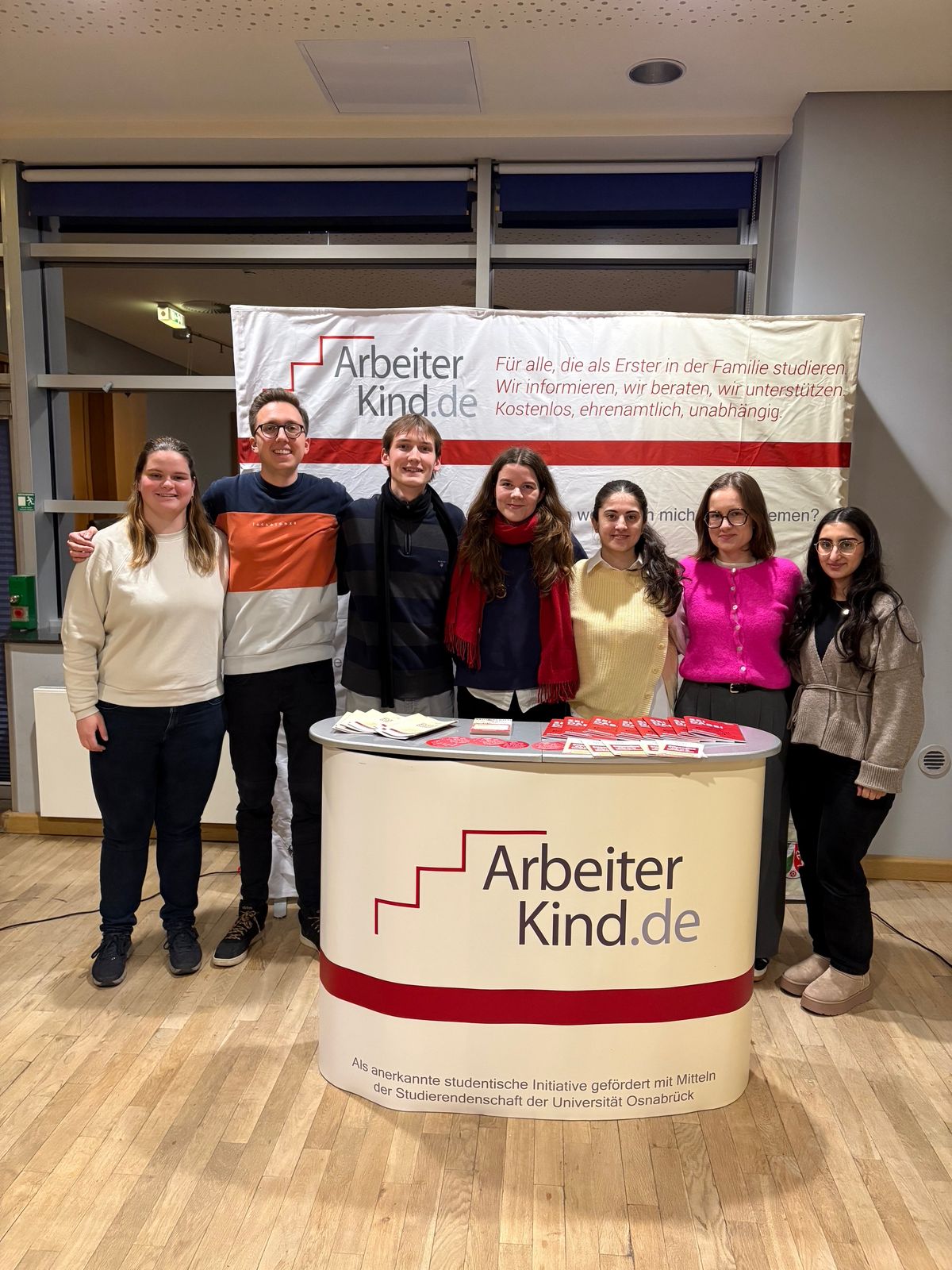 Hier sind Menschen der Gruppe Münster zu sehen, wie sie an einem Messestand stehen.