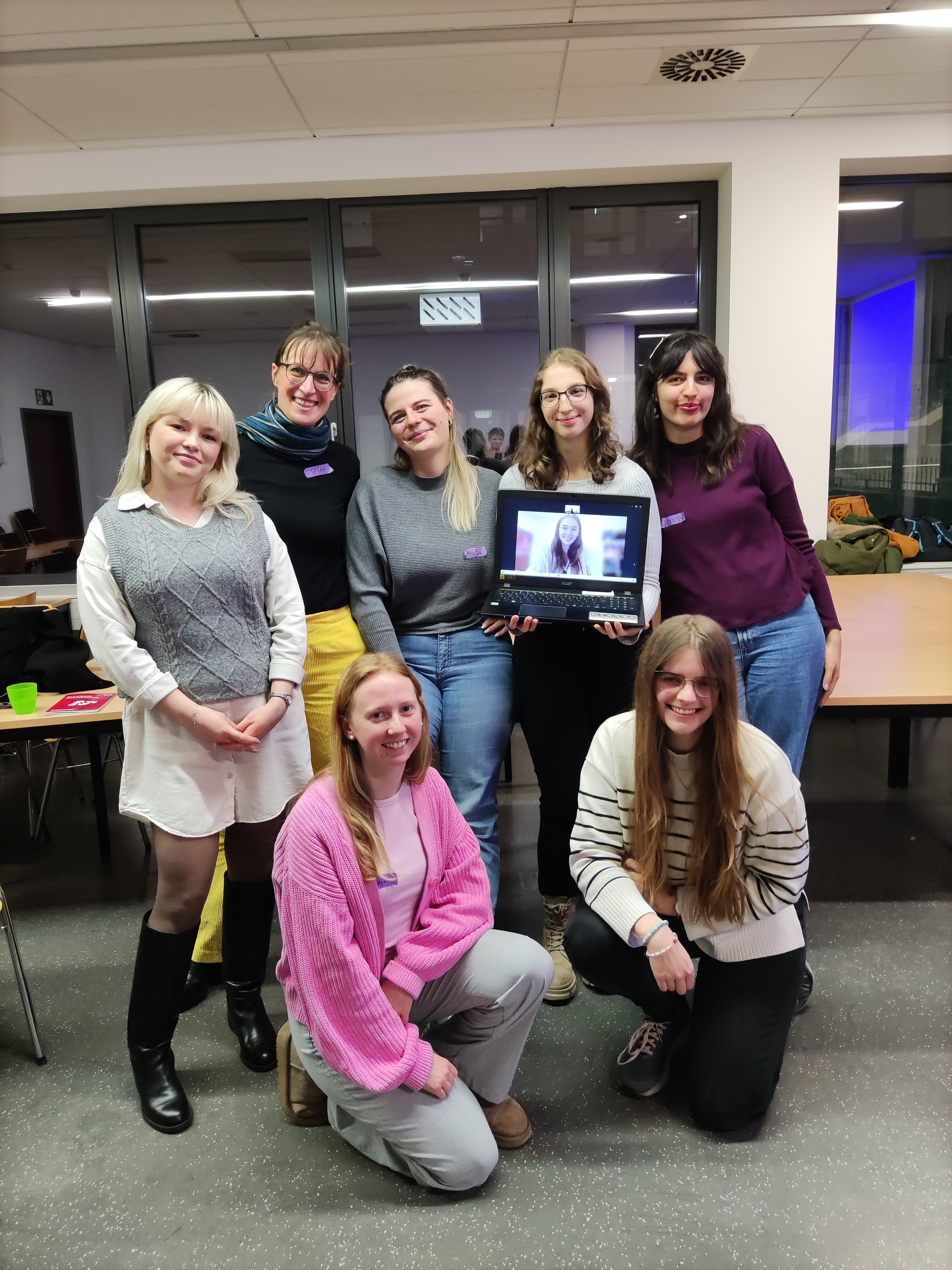 Mitglieder der Arbeiterkind-Gruppe stehen zusammen und posieren für ein Gruppenfoto. Es sind 8 Mitglieder, eine wurde online per Zoom dazugeschaltet.