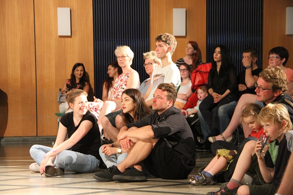 Schulaufnahme des Overberg-Kollegs auf der Schülerinnen und Schüler auf dem Boden sitzen und gespannt in eine Richtung schauen.