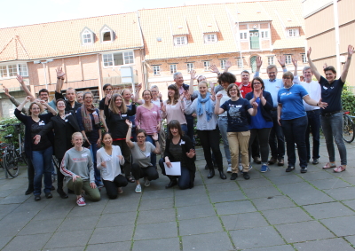 Gruppenbild mit rund 25 Menschen, die lachen und ihre Händ ein die Luft heben. (Foto: ArbeiterKind.de) 