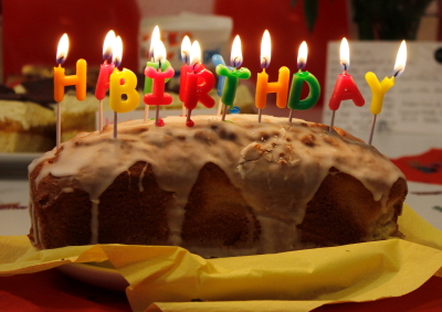Kuchenbild: Ein Zitronenkuchen in Kastenform mit brennenden Kerzen in Buchstabenform. Und da steht Happy Birthday. (Foto: ArbeiterKind.de)